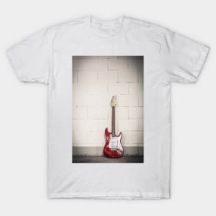 Red electric guitar against white brick wall background T-Shirt